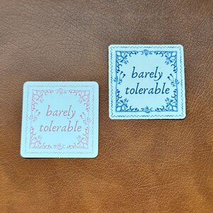 May include: Two square white cards with decorative borders. The top card has a blue border and the text "barely tolerable" in blue. The bottom card has a pink border and the text "barely tolerable" in pink.