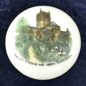 May include: A white ceramic round trinket box with a black and white image of the Italian Gardens and Abbey in Tewkesbury. The image is surrounded by a green border.
