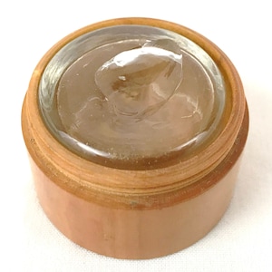 May include: A wooden container with a clear glass lid. The lid has a small amount of clear gel inside.