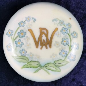 May include: A white porcelain lid with a gold monogram "VW" surrounded by a wreath of blue forget-me-not flowers.