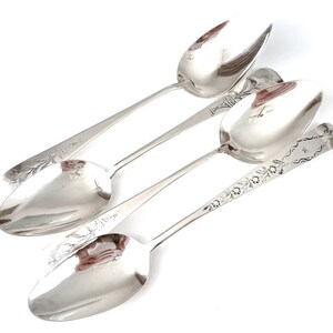 Puede incluir: Tres cucharas de plata con diseños florales ornamentados en los mangos. Las cucharas están dispuestas en una pila, con el cuenco de la cuchara superior mirando hacia el espectador.