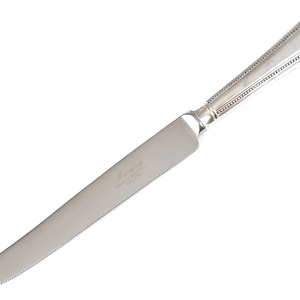 May include: Silver serrated bread knife with a beaded handle. The knife is engraved with the text "Meredith Made in Sheffield England".
