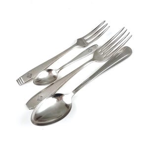 May include: A set of three silver-plated utensils, including two forks and a spoon. The utensils have a simple, elegant design and feature a small square logo on the handle.