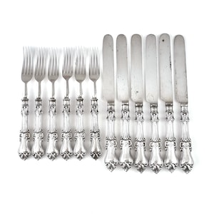 May include: A set of 10 silver-plated forks and knives with ornate handles. The handles have a floral design and are polished to a shine.