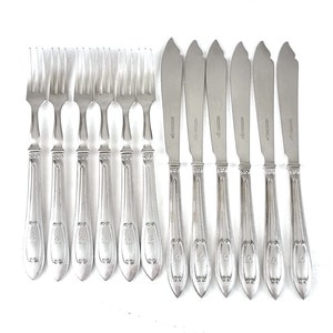 May include: Set of ten silver-plated cutlery, including eight forks and two butter knives. The forks have ornate handles with a decorative design. The knives have a similar design on the handles and a pointed blade.