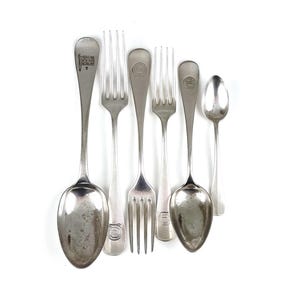 May include: A set of six silver-plated cutlery pieces, including a spoon, a fork, and four knives. The cutlery is engraved with a crest and a flag.