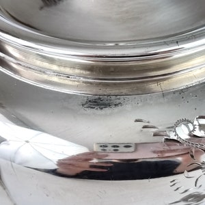 May include: Close-up of the bottom of a silver serving dish with a decorative floral design.
