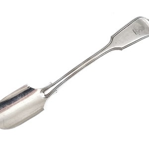 May include: A silver serving spoon with a scoop-shaped bowl and a long, slender handle. The handle has a decorative design and a small engraved crest.