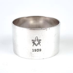 Könnte beinhalten: Silberner Serviettenring mit einem freimaurerischen Symbol und der eingravierten Jahreszahl 1939.