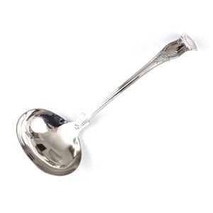 May include: A silver ladle with a long handle and a decorative design on the top. The ladle is made of polished metal and has a smooth, rounded bowl.