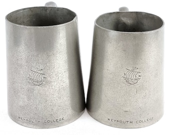 Puede incluir: Dos jarras de peltre plateadas con un diseño de barco y las palabras "Weymouth College" en la parte inferior.