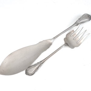 Op de afbeelding: Een zilveren serveerset met een mes en vork. De handvatten zijn versierd en de bladen zijn gepolijst.