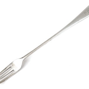 May include: A silver serving fork with a long handle and a pointed end. The handle has the inscription "The New Star Sheffield" on it.