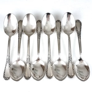 Può includere: Set di otto cucchiai d'argento con manici decorati. I cucchiai hanno un design classico e sono perfetti per servire dessert o altri piccoli piatti.
