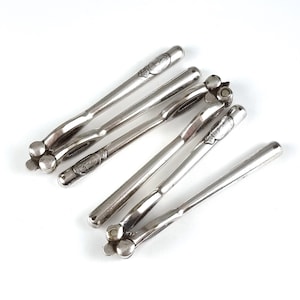 Puede incluir: Un juego de seis cascanueces de plata con diseños intrincados. Los cascanueces están dispuestos en forma de abanico, con los mangos apuntando hacia afuera.