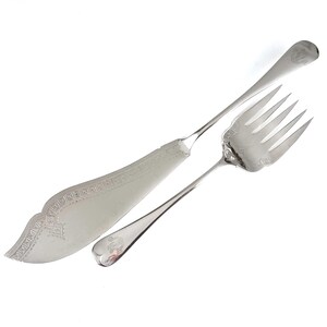 May include: A silver serving set with a knife and fork. The knife has a decorative handle and the fork has a decorative design on the tines.