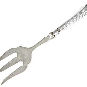 Peut inclure: Une fourchette de service en argent avec un manche décoratif. Le manche est orné d'un motif cannelé et d'un bouton en forme de coquille.