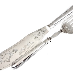 Puede incluir: Un juego de servicio de plata con un diseño ornamentado. El cuchillo y el tenedor tienen mangos con cuentas y están grabados con motivos florales.