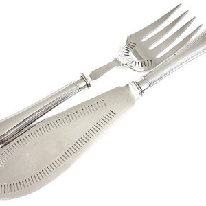Puede incluir: Un juego de cubiertos de pescado de plata con cuchillo y tenedor. El cuchillo tiene una hoja decorativa perforada y el tenedor tiene cuatro dientes.