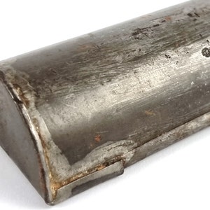 Pu&ograve; includere: Primo piano di un tubo metallico con un'estremit&agrave; arrotondata. Il tubo &egrave; in metallo argentato e ha un aspetto usurato e invecchiato. Il tubo &egrave; leggermente ammaccato e graffiato.