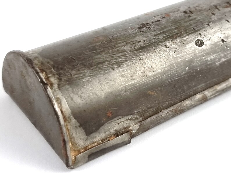 Pu&ograve; includere: Primo piano di un tubo metallico con un'estremit&agrave; arrotondata. Il tubo &egrave; in metallo argentato e ha un aspetto usurato e invecchiato. Il tubo &egrave; leggermente ammaccato e graffiato.