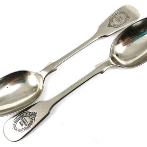 Könnte beinhalten: Zwei silberne Löffel mit verzierten Griffen. Die Löffel sind mit dem Text "S. MIDDLEFIELD & SONS, BIRMINGHAM" und "THE LONDON & BIRMINGHAM SILVER CO. LTD." graviert.