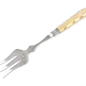 May include: A silver fork with an ornate design and a bone handle. The fork has three tines and is approximately 18 cm long.