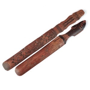 May include: Two wooden carving tools with intricate designs. One tool features a floral pattern and the other has a fish design.