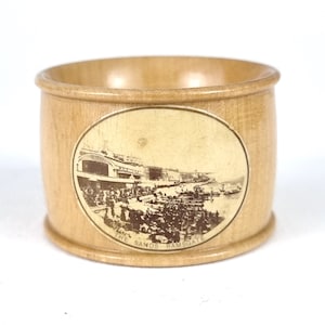 May include: A wooden napkin ring with a vintage photo of a seaside town. The photo shows a building with the text "The Sands Ramsgate".