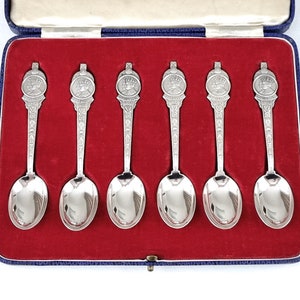 Puede incluir: Juego de seis cucharaditas de plata en una caja forrada de terciopelo rojo. Cada cuchara presenta un diseño detallado de una pareja real.