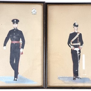 May include: Two framed watercolour paintings depicting military officers in uniform. The officer on the left is wearing a dark blue uniform with a red sash and a black hat. The officer on the right is wearing a dark blue uniform with a red sash and a black hat with a plume. Both paintings include the text "The Royal Army Ordnance Corps".