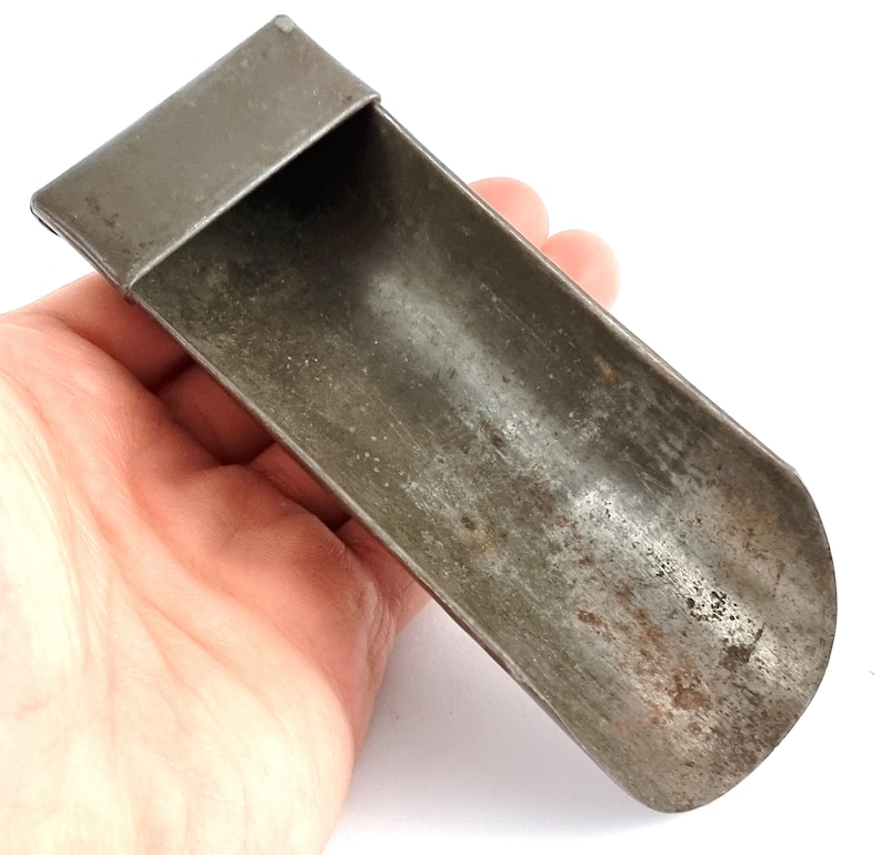 Pu&ograve; includere: Una paletta in metallo vintage con un'estremit&agrave; arrotondata e una parte superiore piatta. La paletta &egrave; in metallo e ha un aspetto usurato e invecchiato.