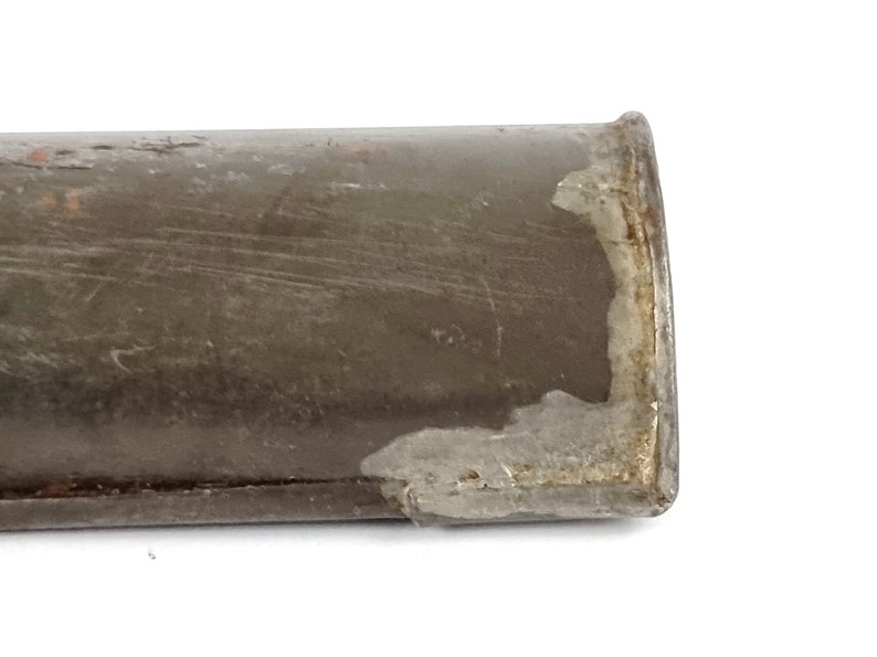 Pu&ograve; includere: Primo piano dell'estremit&agrave; di un tubo metallico marrone con parte della vernice scheggiata, che rivela il metallo sottostante.