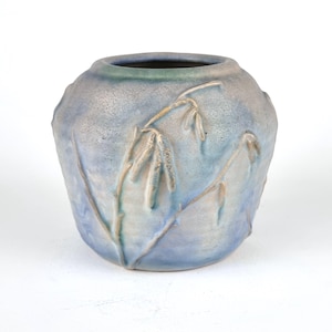 May include: A blue and brown ceramic vase with a textured surface and a design of stylized branches with leaves.