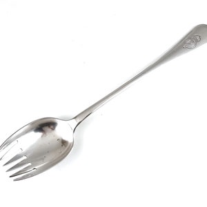 May include: A silver serving spoon with a fork at the end. The handle is decorated with a small design.