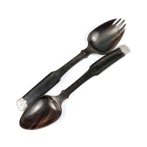 Puede incluir: Un juego de dos servidores de ensalada de cuerno negro con detalles plateados. Los servidores son una cuchara y un tenedor.