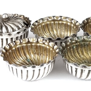 Puede incluir: Un juego de cinco saleros de plata con un plato para condimentos con tapa. Los saleros tienen un diseño acanalado y un borde festoneado. El plato para condimentos tiene una tapa acanalada y un asa.