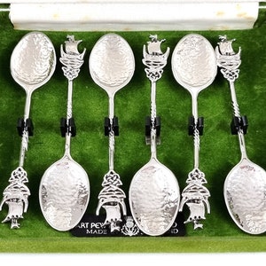 May include: Set of six silver spoons with a Celtic knot design and a ship on the handle. The spoons are in a green velvet box with the words "Art Pewter Made" on the bottom.