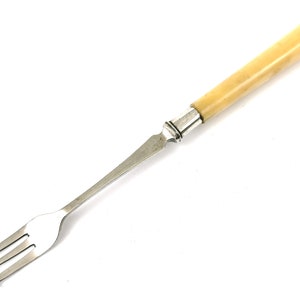 May include: A silver fork with a bone handle. The fork has three prongs and is designed for serving food.