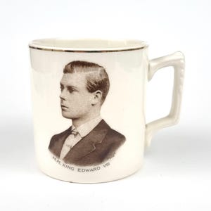 Puede incluir: Taza de cerámica color crema con un retrato en sepia de un hombre con traje. La taza tiene un borde dorado y un asa decorativa. El texto "H.M. King Edward VIII" está impreso debajo. Un objeto de colección vintage.