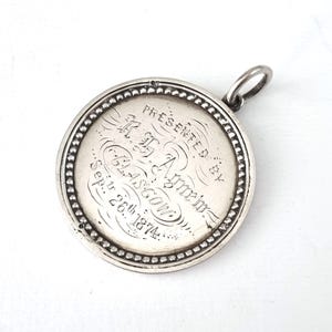 May include: Silver pendant with an inscription that reads "Presented by the Amm. of the 62nd. Ascon. Sept. 26th 1874."