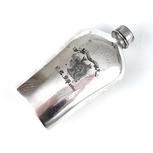 Könnte beinhalten: Silberne Flachmann mit einem gravierten Design eines Hirsches und dem Text "Royal Arms C.M.S.A. Maker."