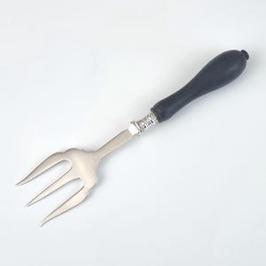 May include: A silver fork with a black wooden handle. The fork has three tines and a decorative design on the handle.