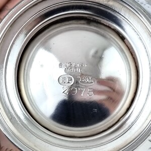 May include: Close-up of the bottom of a silver object with the inscription "English Made" and the numbers "2975".