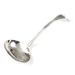 May include: A silver-colored ladle with a long, curved handle and a rounded bowl. The handle features a decorative floral design at the end. The ladle is made of a shiny, reflective metal, likely stainless steel, and is designed for serving soups or sauces.
