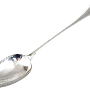 Könnte beinhalten: Ein silberner Löffel mit einem langen, schlanken Stiel und einer abgerundeten Schale. Der Löffel ist poliert und glänzend.