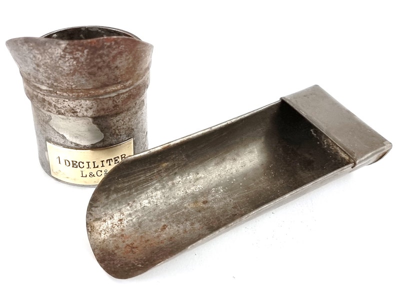 Pu&ograve; includere: Due bicchieri di misura in metallo vintage. Uno &egrave; un bicchiere da 1 decilitro con un'etichetta che recita "1 Decilitro L&Co.". L'altro &egrave; un bicchiere a forma di cucchiaio.