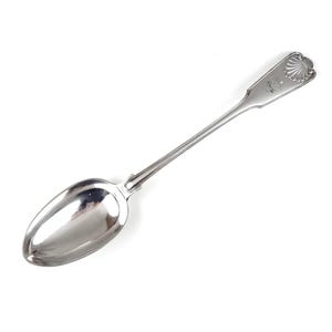 May include: A silver spoon with a shell design on the handle. The spoon has a rounded bowl and a long, slender handle.