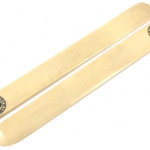 May include: Two ivory shoe horns with black lettering. The lettering reads "TRADE MARK" and "KYNOCH LTD."