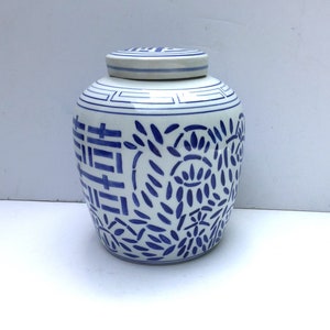 May include: A white ceramic jar with a blue and white floral design. The jar has a lid and features the Chinese character for "double happiness" on the front.